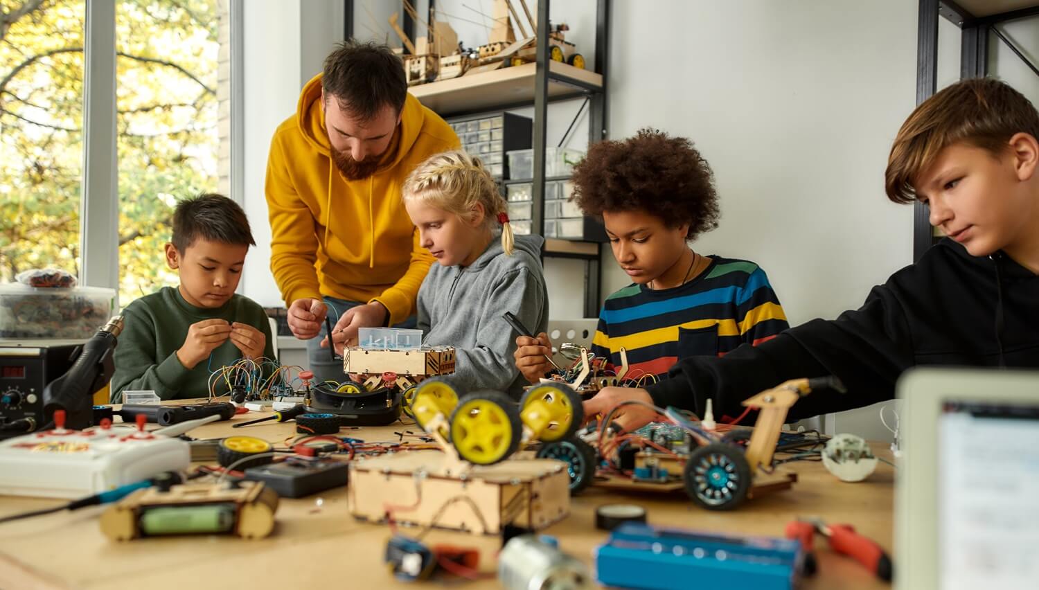 A STEM Teacher works with young students building robots
